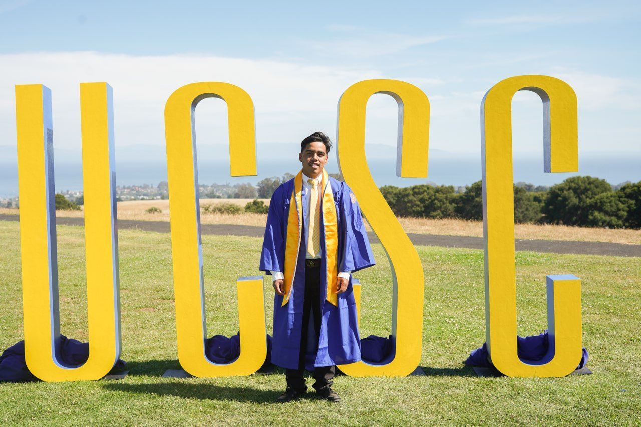 Pedro in front of the UCSC letters on graduation day