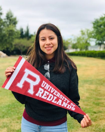 A LoyalTeach student holds a University of Redlands pennant